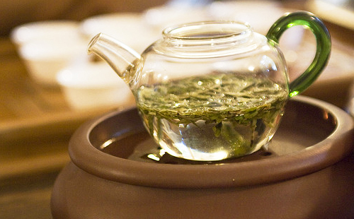 Травяной настой в прозрачном чайнике стоит на водяной бане