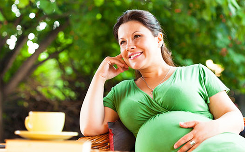 Счастливая беременная женщина в зелёном платье